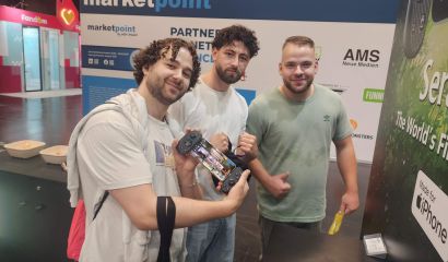 Three Gamescom 2026 attendees posing with the Serafim S3 mobile gaming controller at the Serafim booth in Cologne.