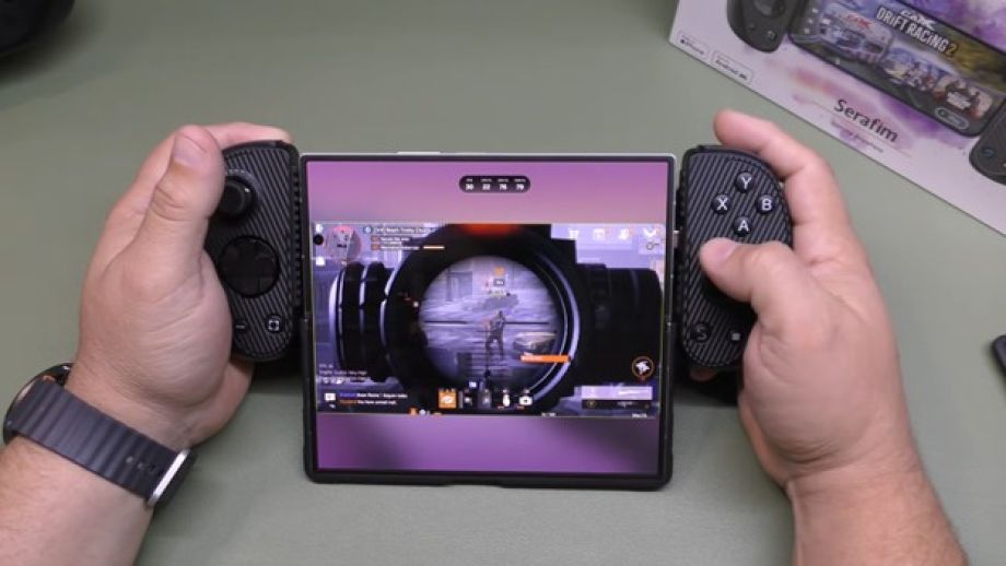 Hands using a mobile gaming controller with a tablet, playing an FPS game with precise aiming and console-style controls