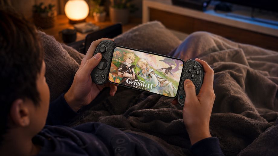 Gamer playing Genshin Impact on a smartphone with a mobile gaming controller while relaxing in bed, showcasing a handheld gaming setup for cloud and mobile gaming.