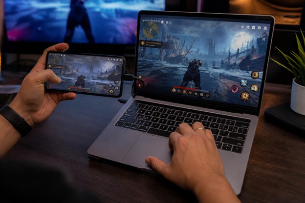 Multi-device gaming experience showing smartphone and laptop running the same action RPG